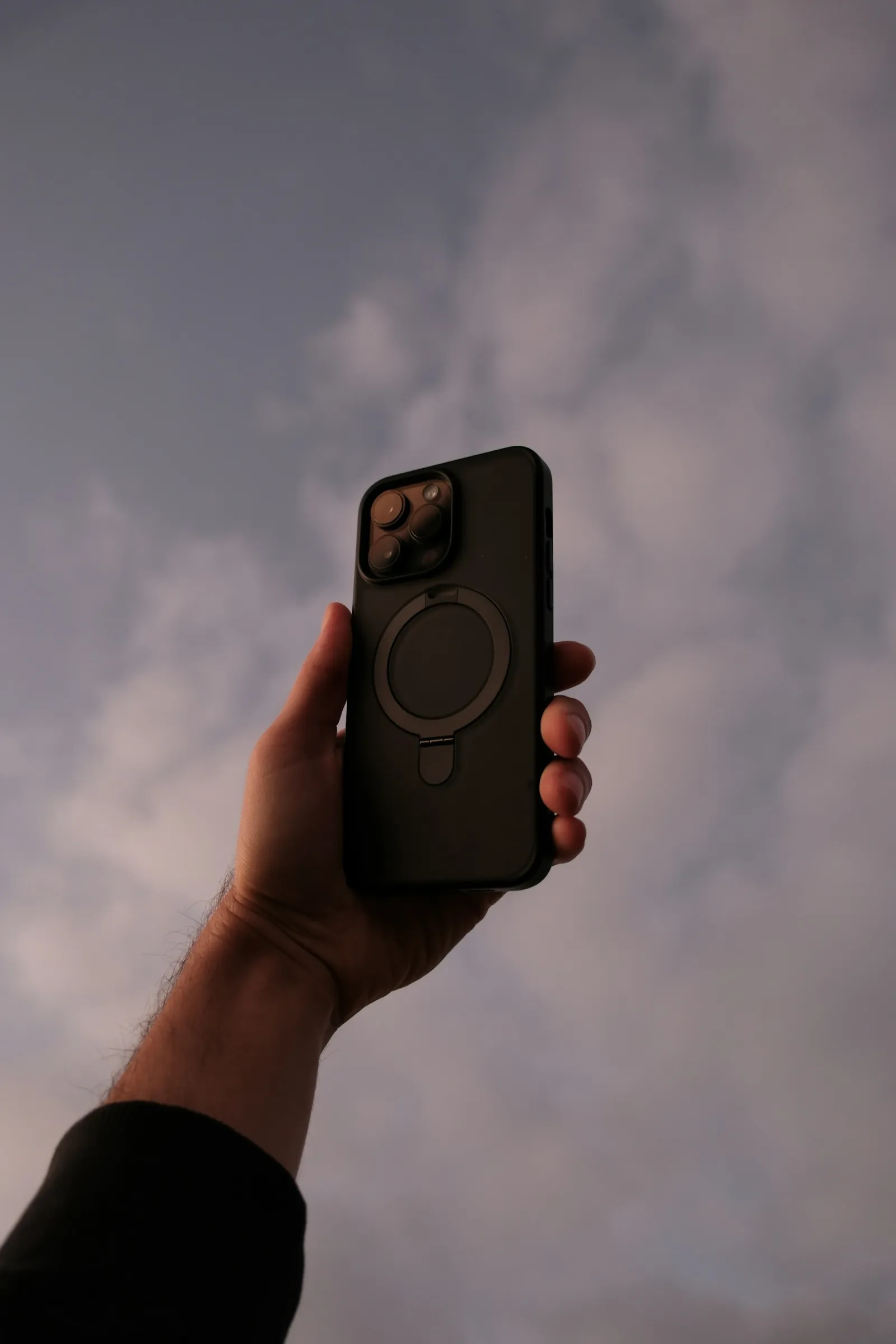 A hand holding a phone outdoors